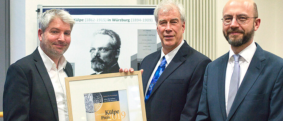 Paul van den Broek (Mitte) hat den Oswald-Külpe-Preis 2019 erhalten. Die Auszeichnung überreichten Tobias Richter (l.), geschäftsführender Vorstand des Instituts für Psychologie, und Roland Deutsch, stellvertretender geschäftsführender Vorstand des Instituts.