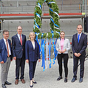 Die Rednerinnen und Redner, die beim Richtfest sprachen, mit der Richtkrone (v.l.): Christian Schuchardt, Paul Pauli, Grit Liebau, Judith Gerlach, Tobias Brixner.