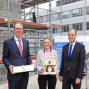 Ministerin Judith Gerlach erhielt von Unipräsident Paul Pauli (l.) und Dekan Tobias Brixner ein Geschenk.