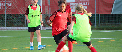 Girls on the football pitch battling for the ball. 
